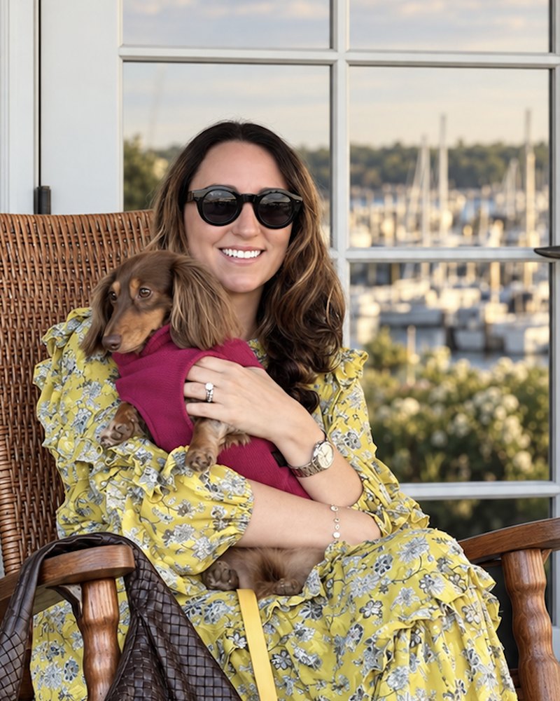 Jillian Shea on a porch in a rocking chair, holding her dachshund