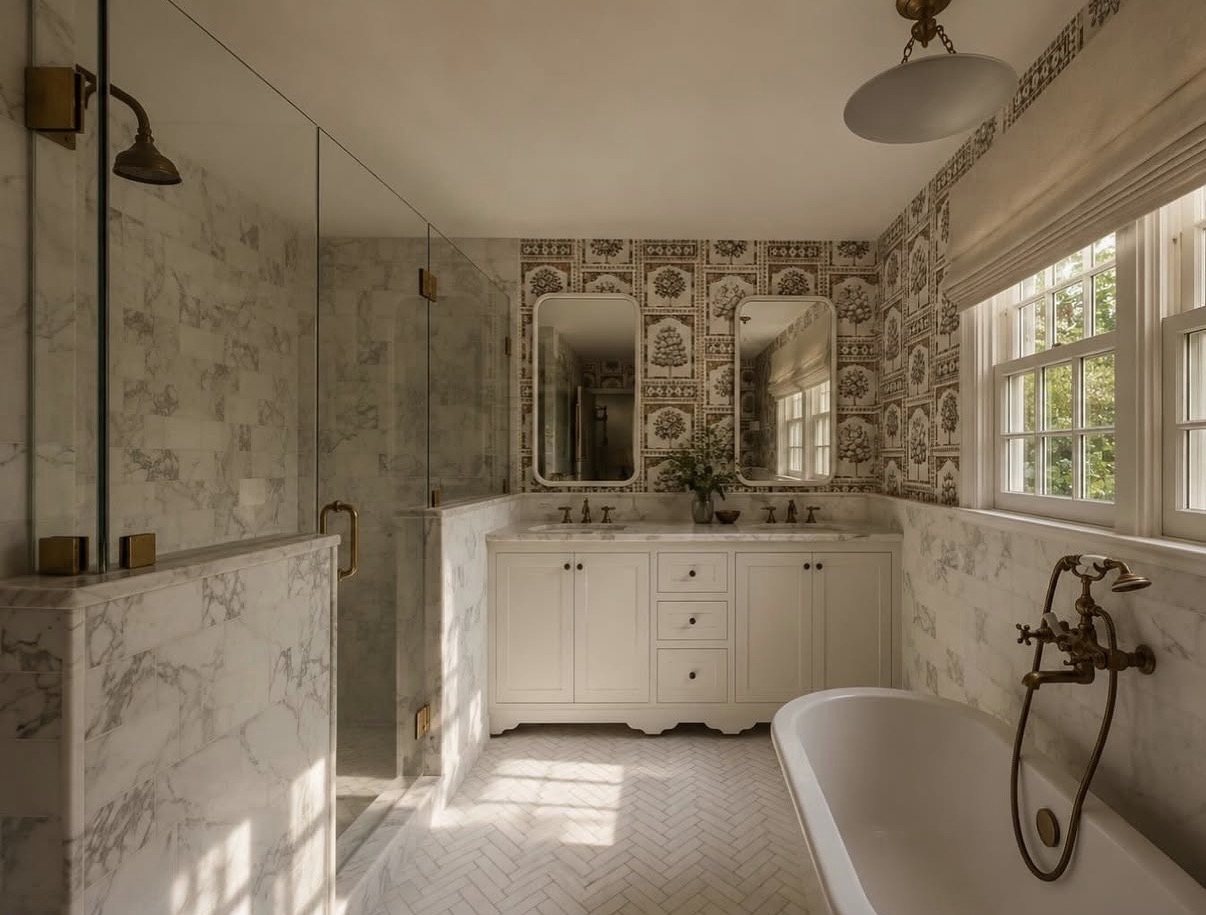 Primary bath with a marble shower, double vanity and toile wallpaper