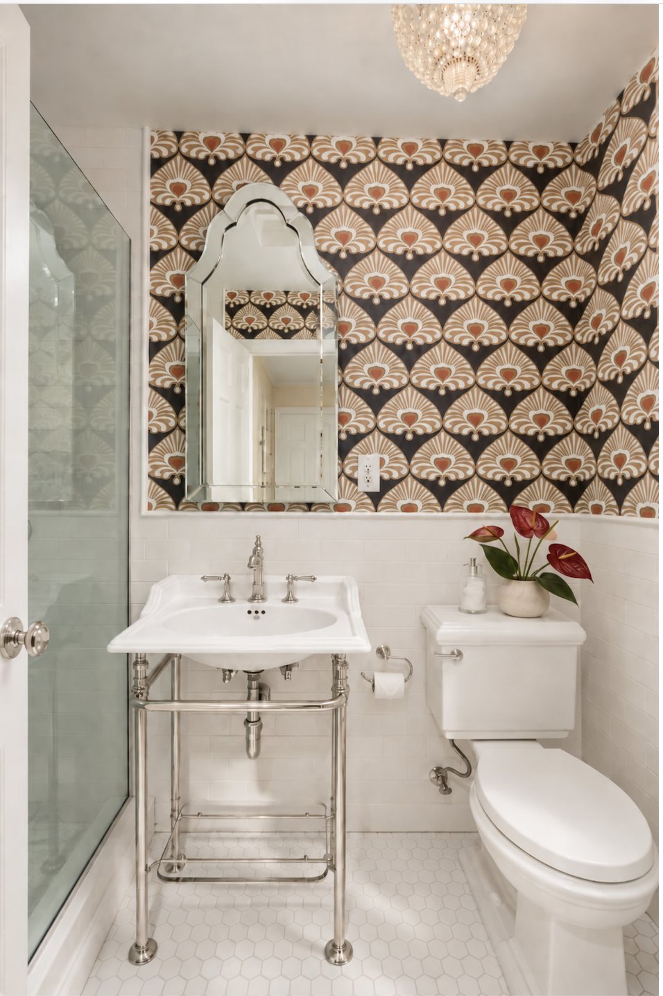 Powder room with bold patterned wallpaper, a console sink and a scalloped mirror